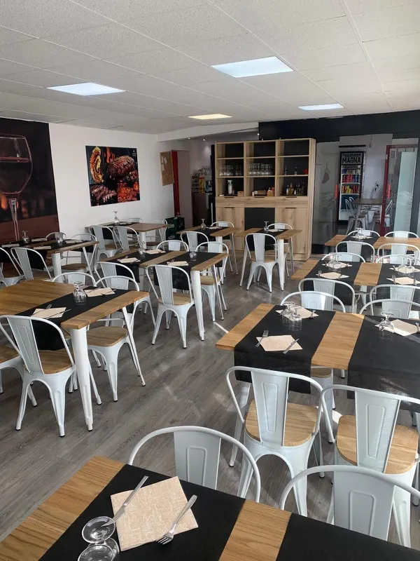 Comedor de La Nostra Braseria con mesas de madera y negro y sillas blancas