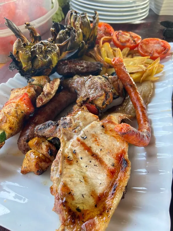 Plato de carnes a la brasa con patatas, tomate y alcachofas